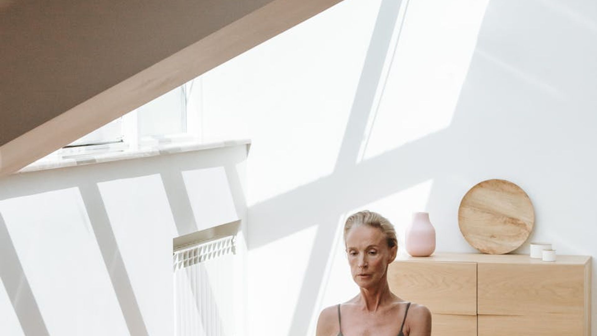 A person practicing yoga at sunrise in a bright room.